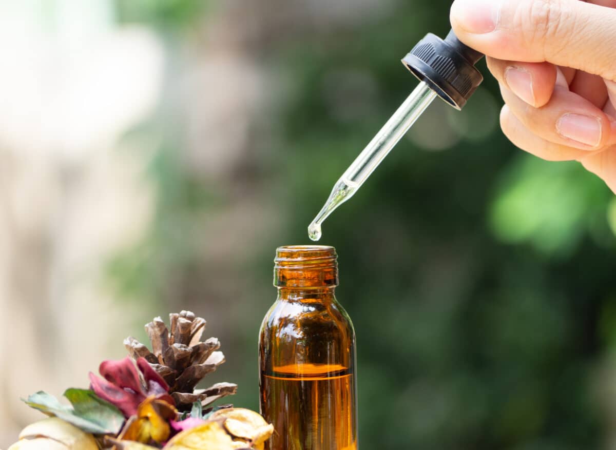 Pipette versant quelques gouttes dans un flacon d’élixir floral ambré
